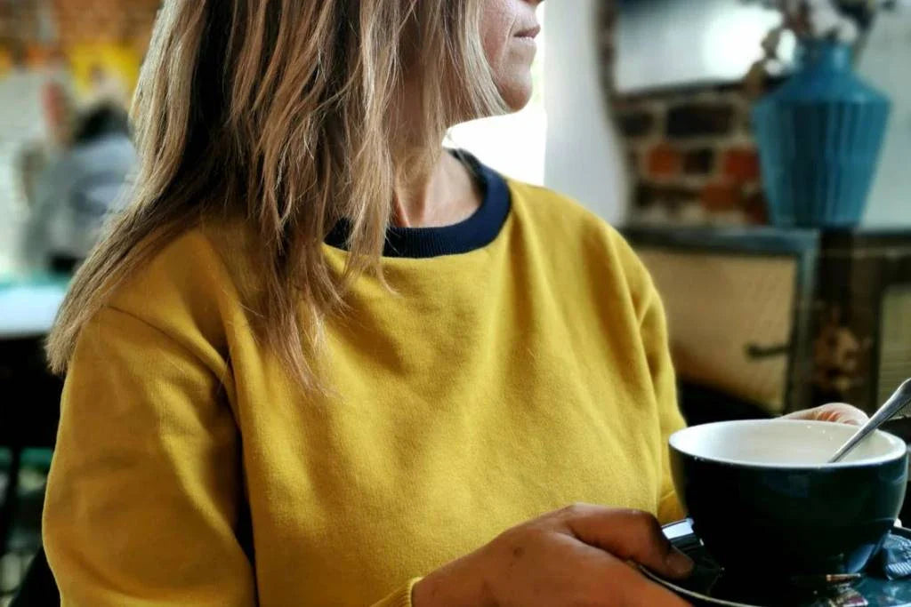 Woman in a coffee shop wearing an aesthete-(kids)wear organic cotton sweatshirt.