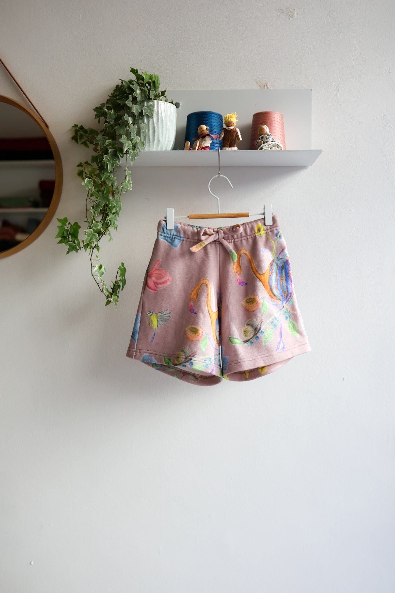 Children's shorts with colorful design hanging on a white wall.