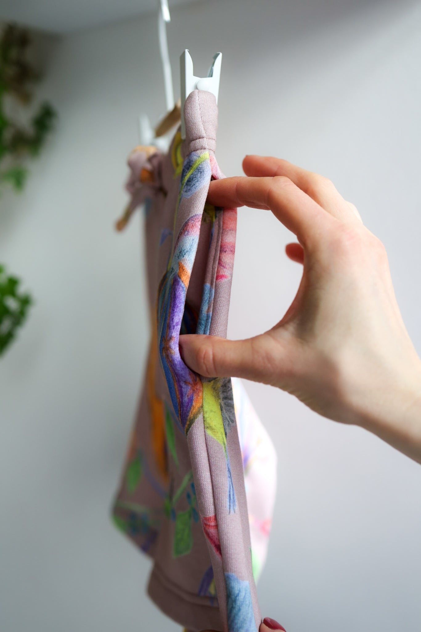 Hand holding a colorful fabric item against a white background