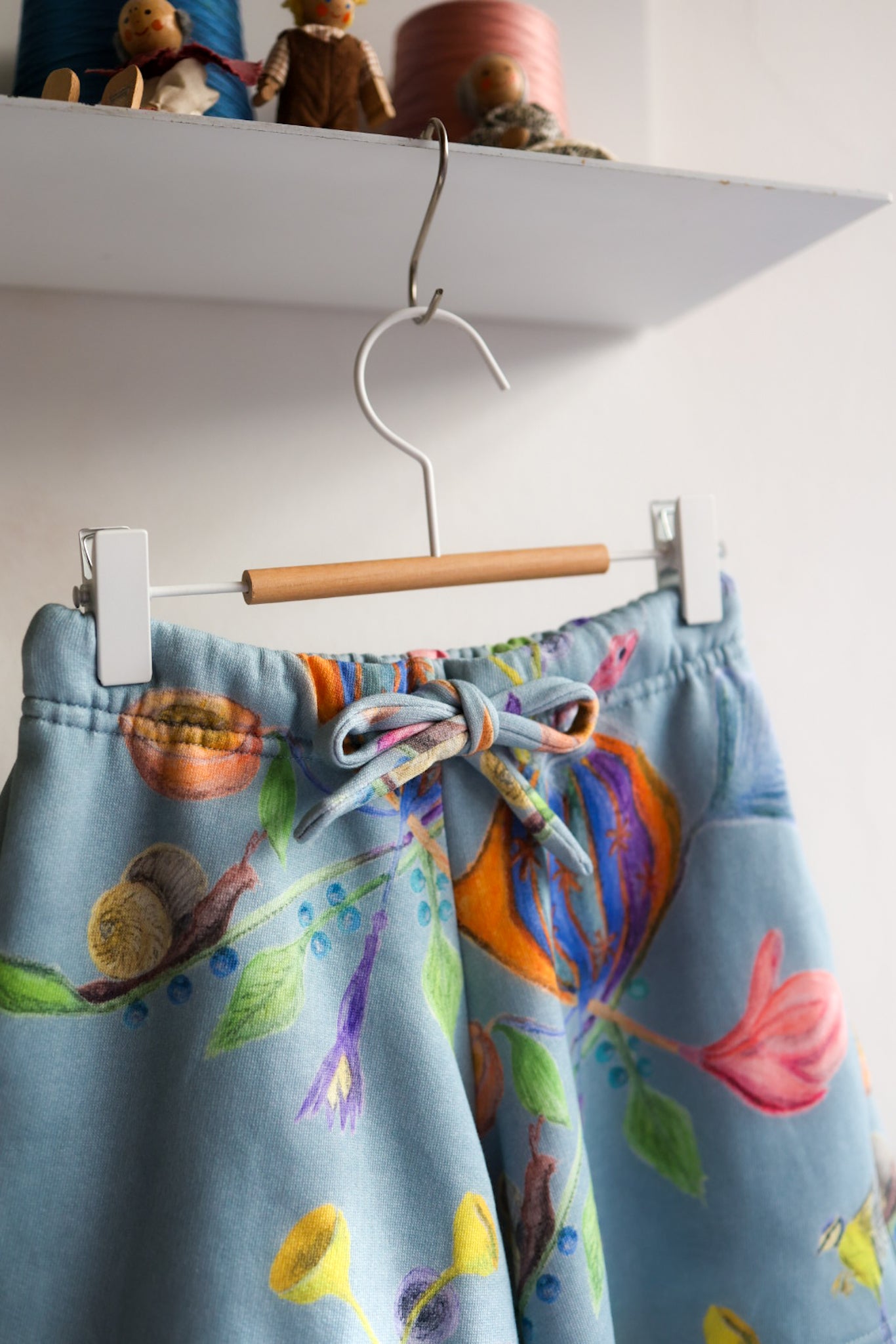Colorful shorts with a floral pattern hanging on a white wall.