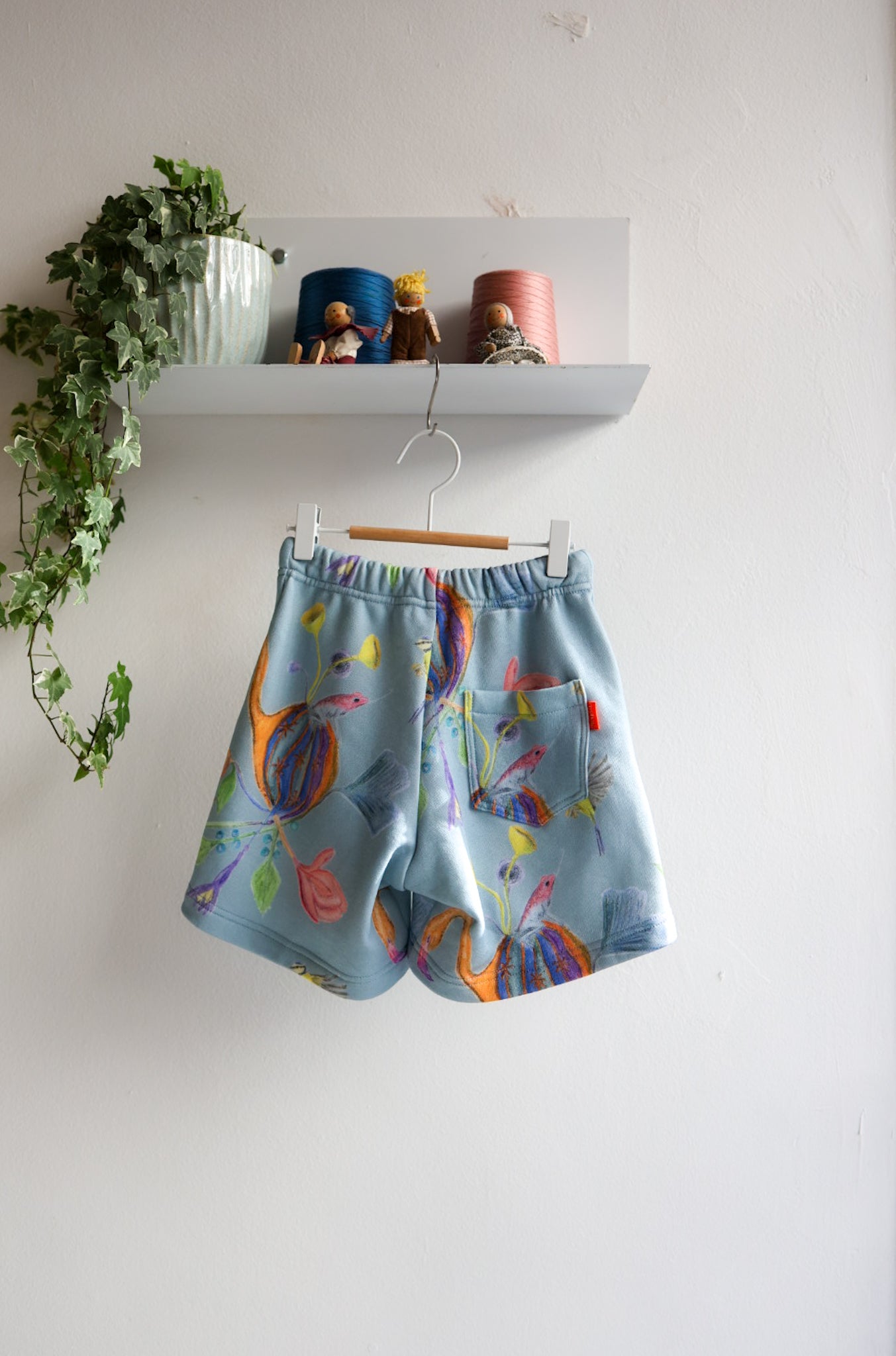 Colorful shorts with a floral pattern hanging on a white wall.