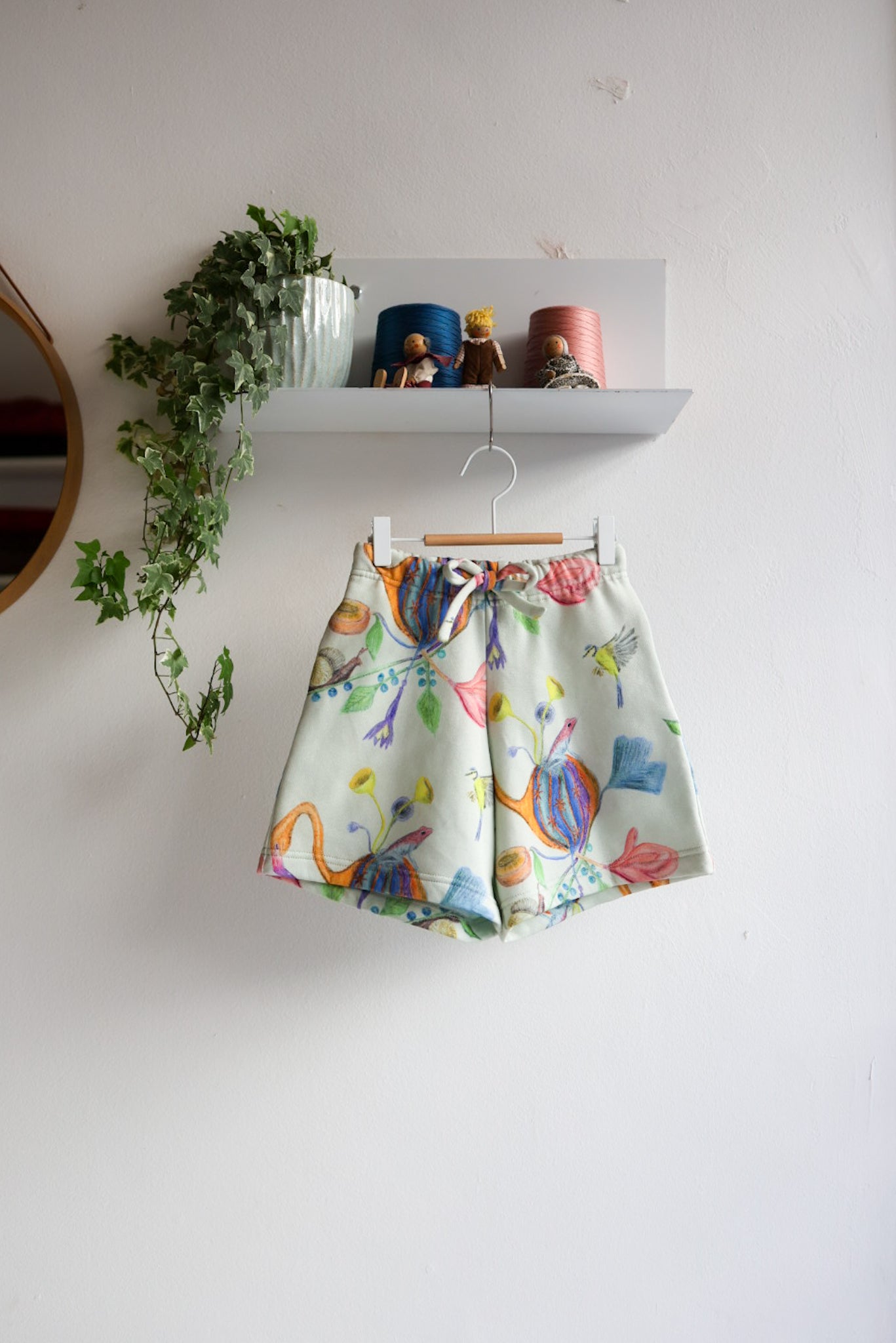 Colorful skirt with animal pattern hanging on a white wall.