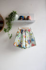 Colorful skirt with animal pattern hanging on a white wall.