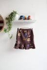 Kids skirt with nature pattern on a hanger against a white wall with decorative items.