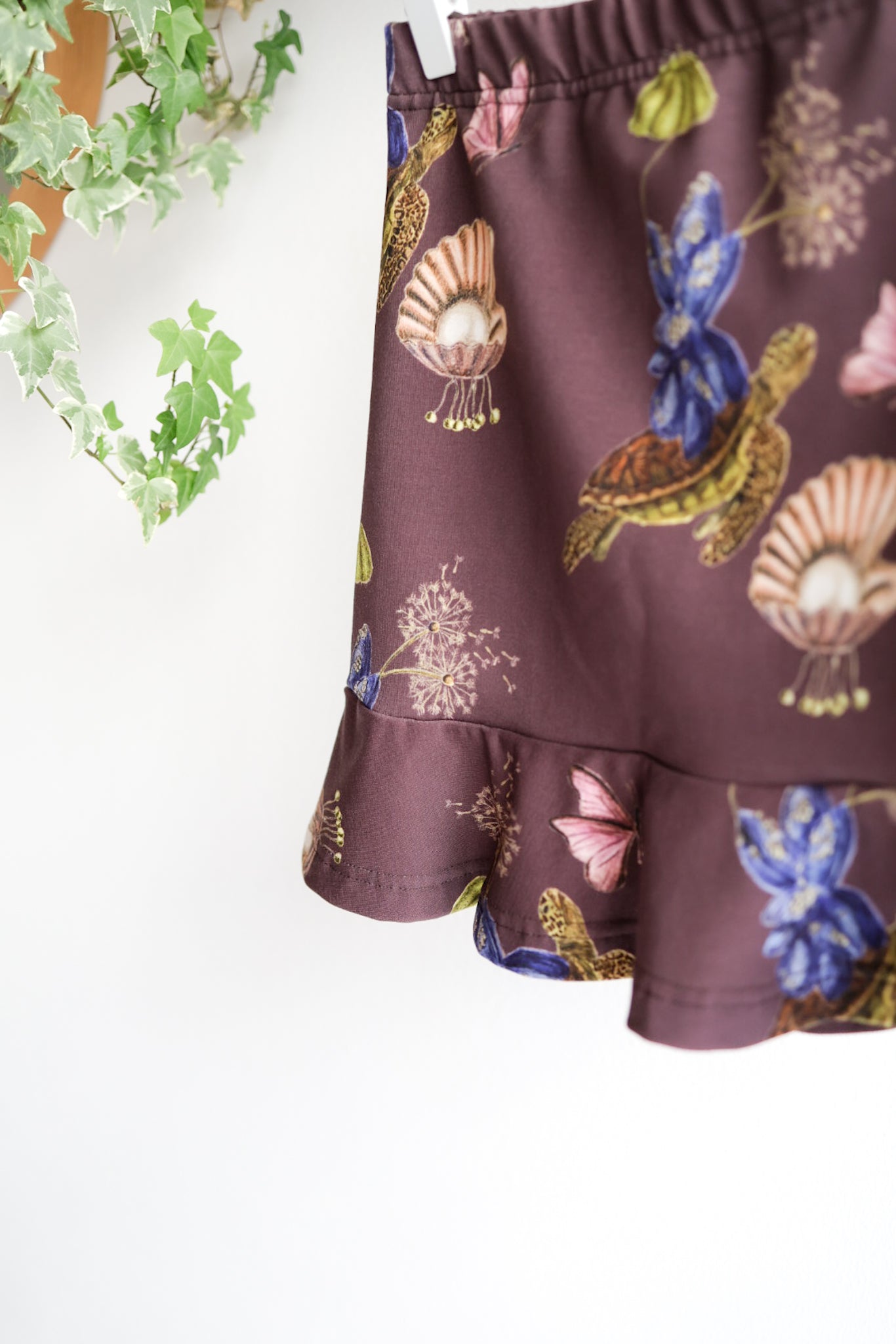Close-up of a kids skirt with nature pattern against a white wall.