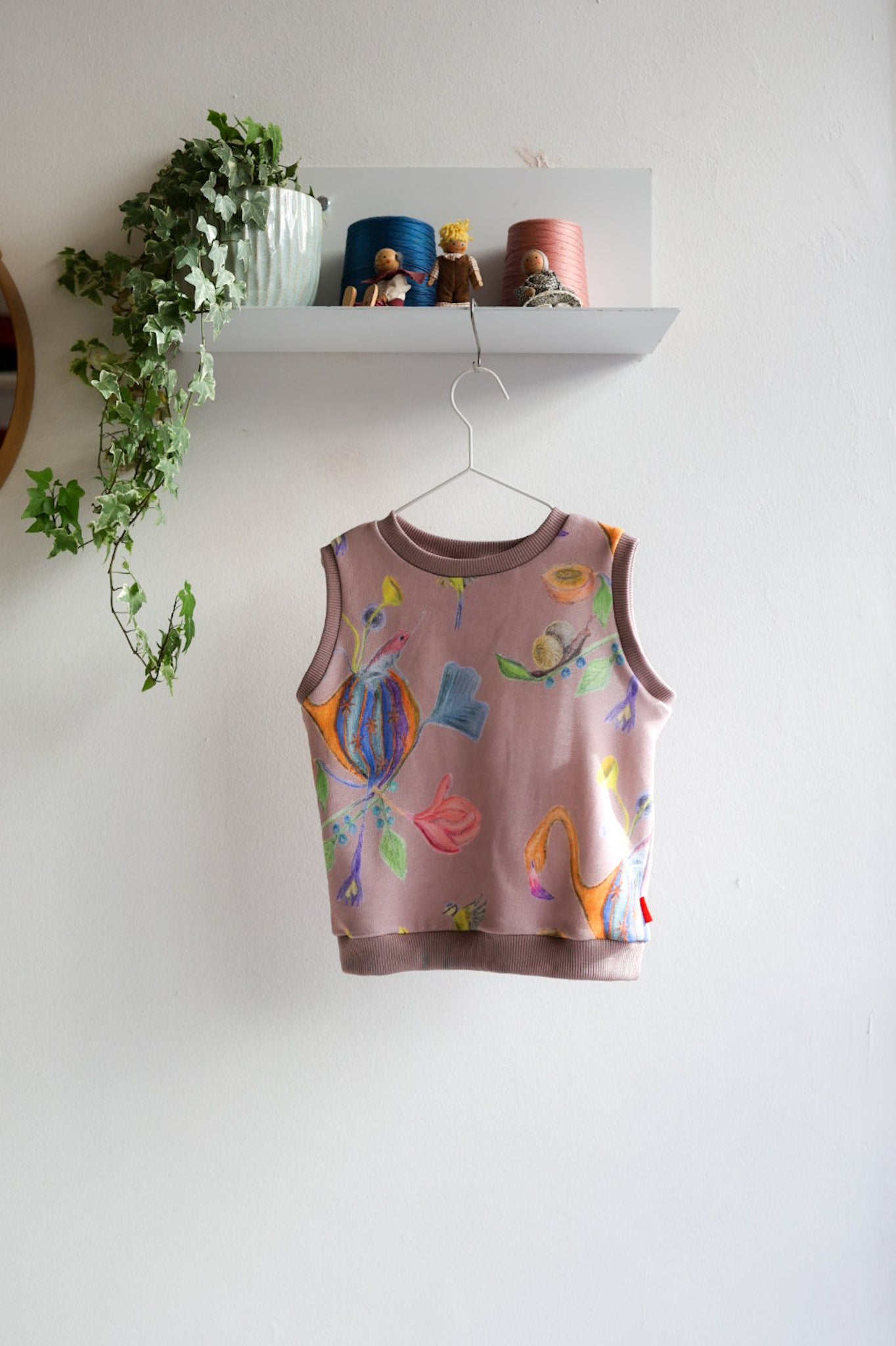 Children's sleeveless top with colorful designs on a white wall.