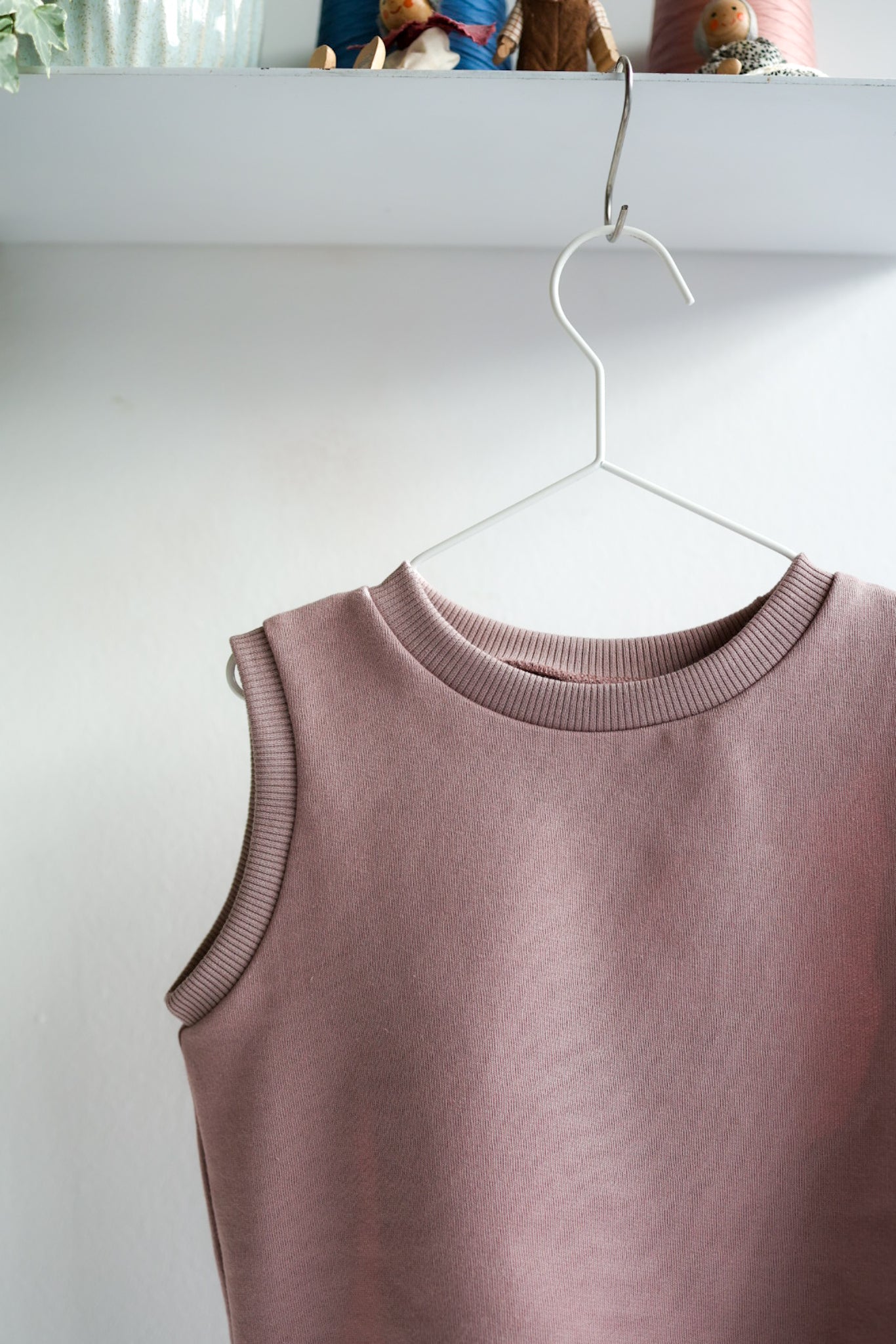 Mauve kids sleeveless top on a white hanger against a white background.