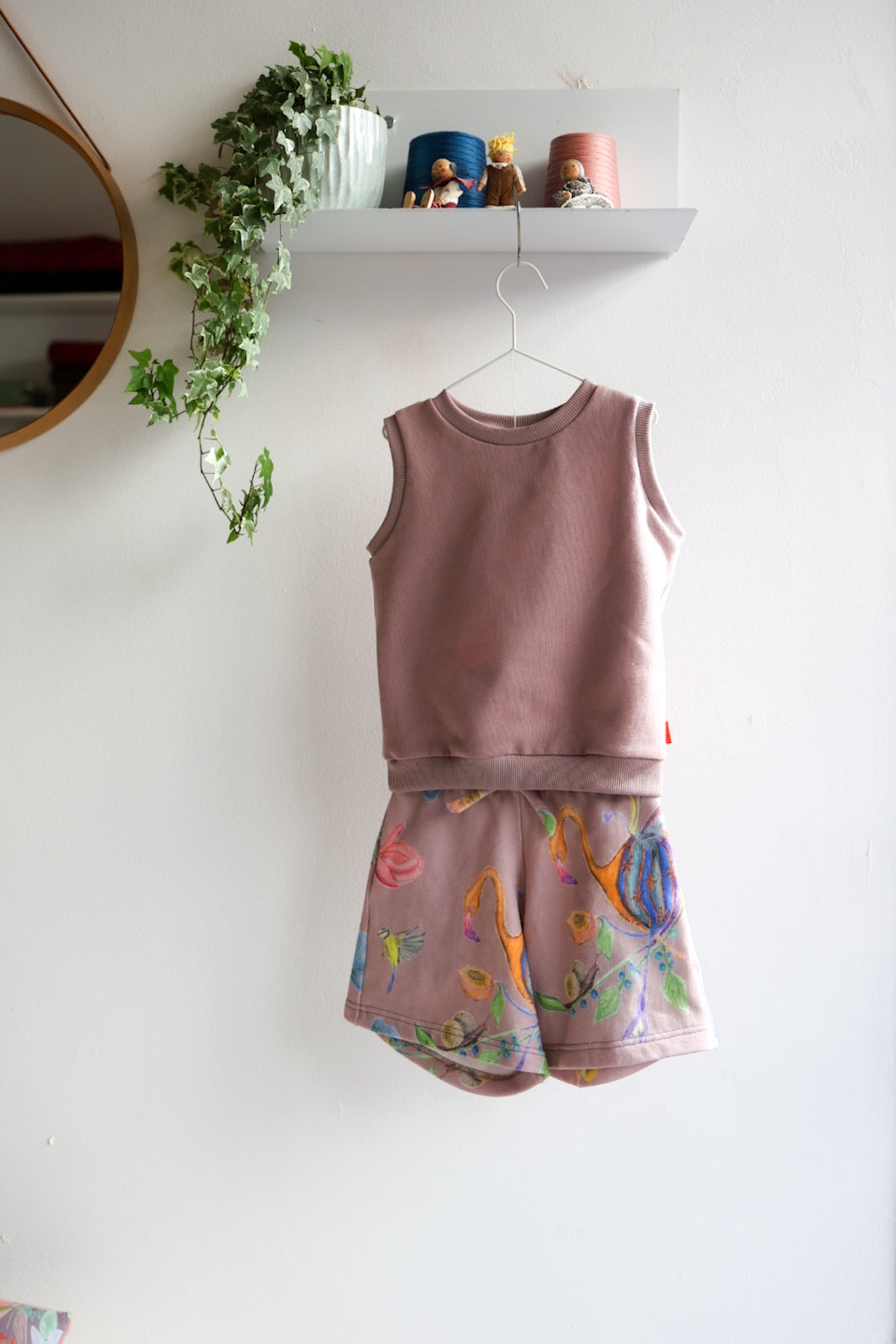 Kids sleeveless top and shorts set with colorful design on a white wall.