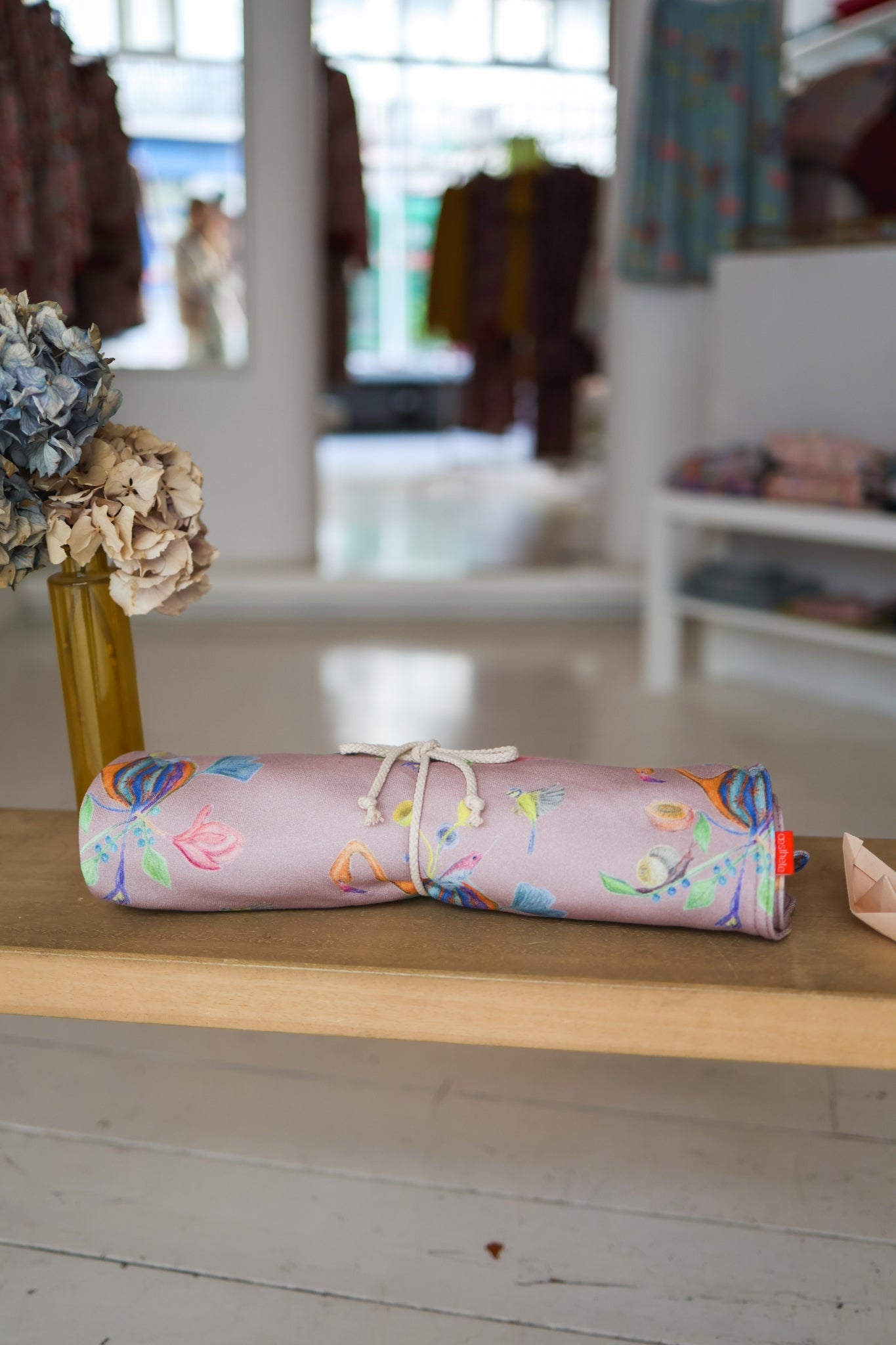 Rolled-up colorful babies blanket on a wooden surface with a blurred indoor background