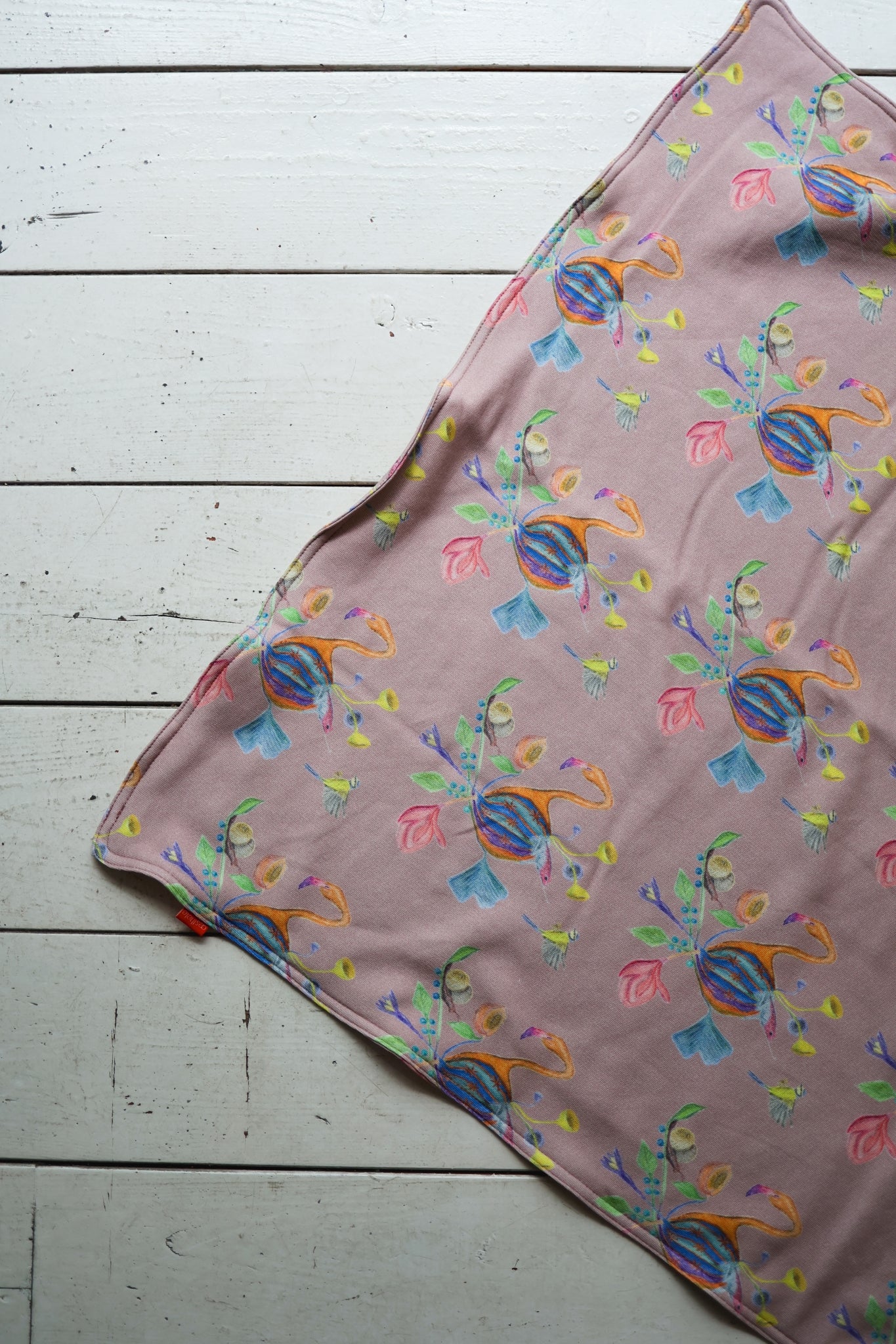 Colorful patterned babies blanket on a white wooden surface.