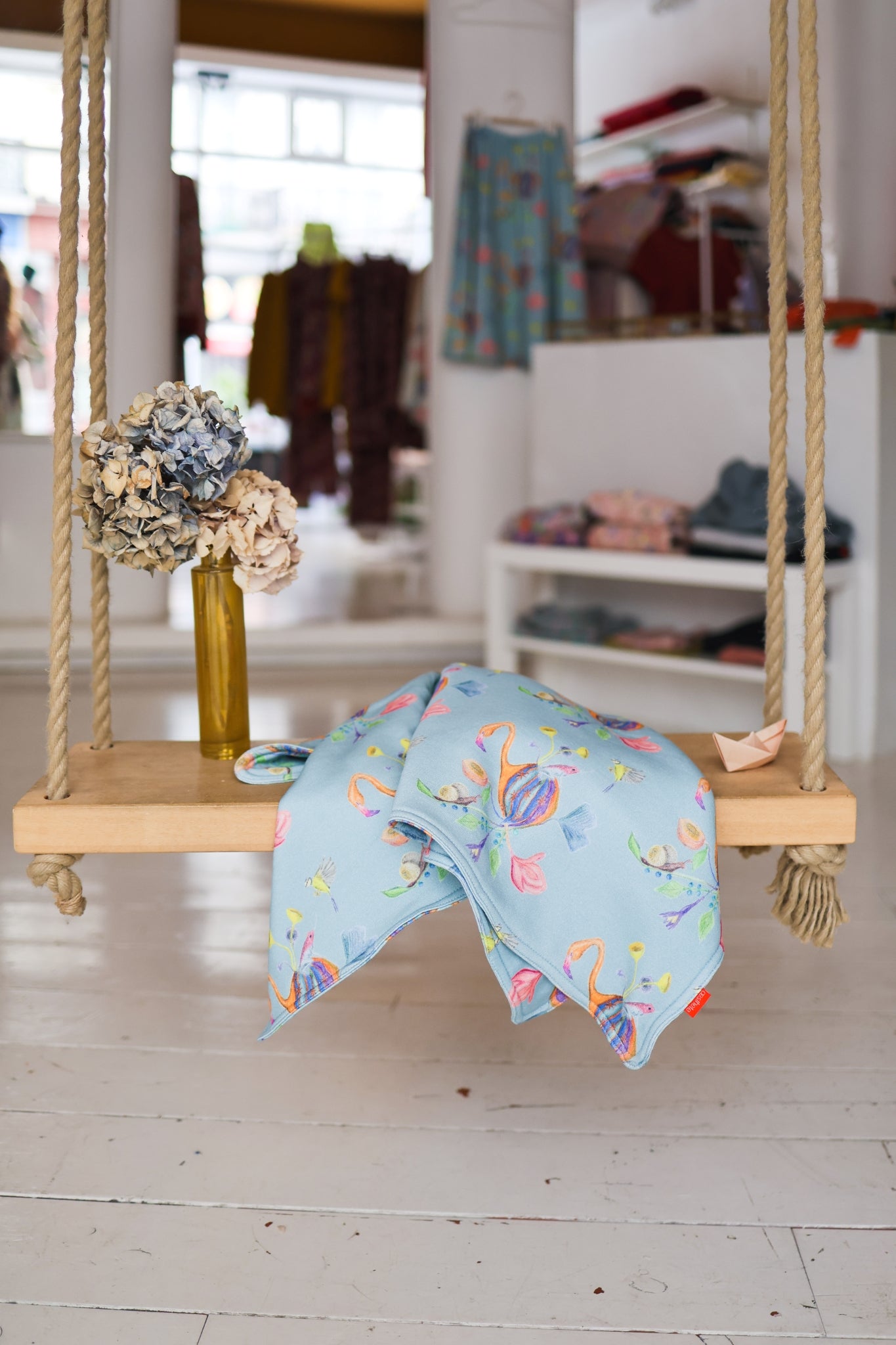 Swing with a colorful babies blanket and decorative items in a store setting.