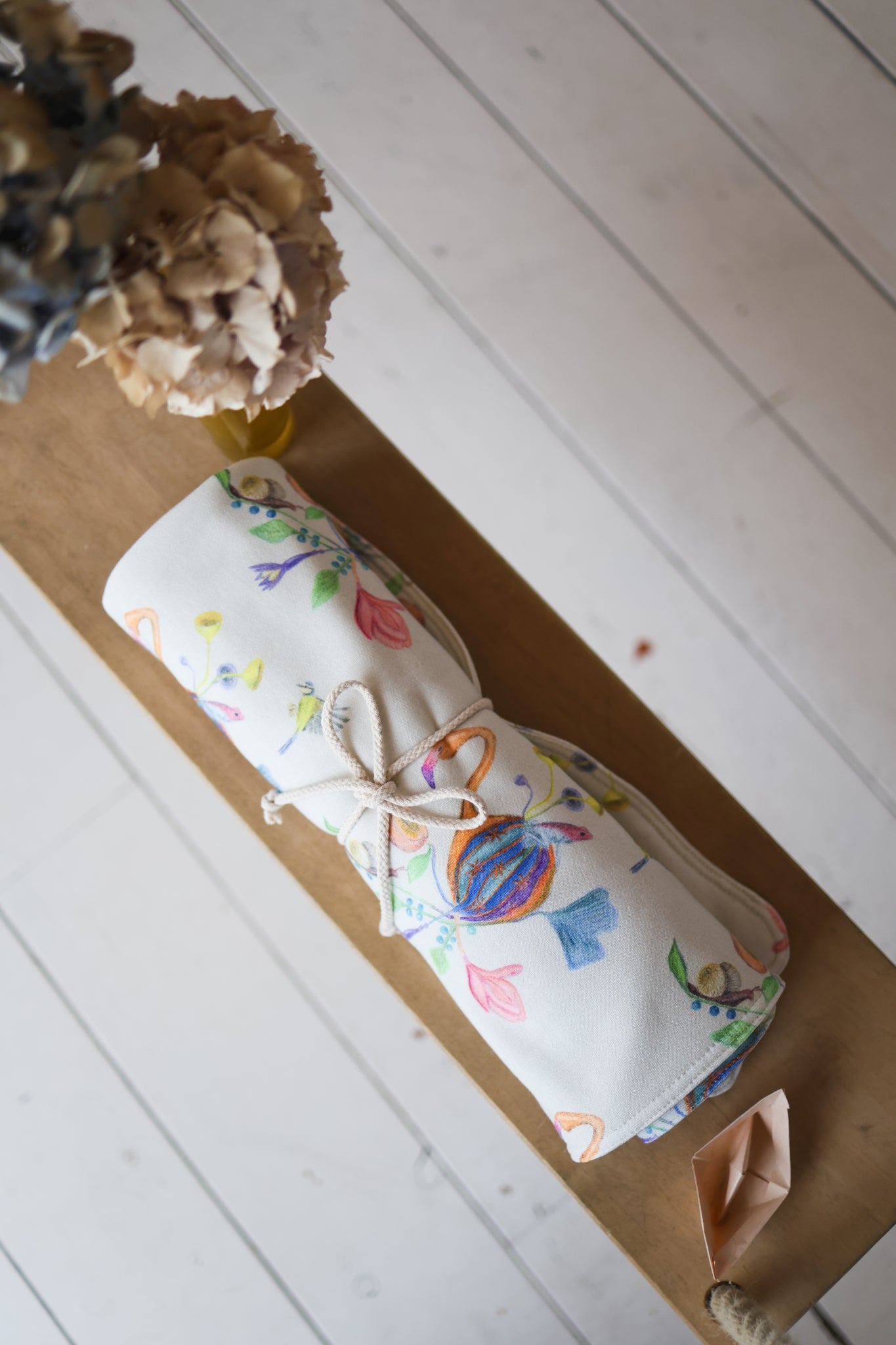 Rolled-up babies blanket with colorful designs on a wooden surface.