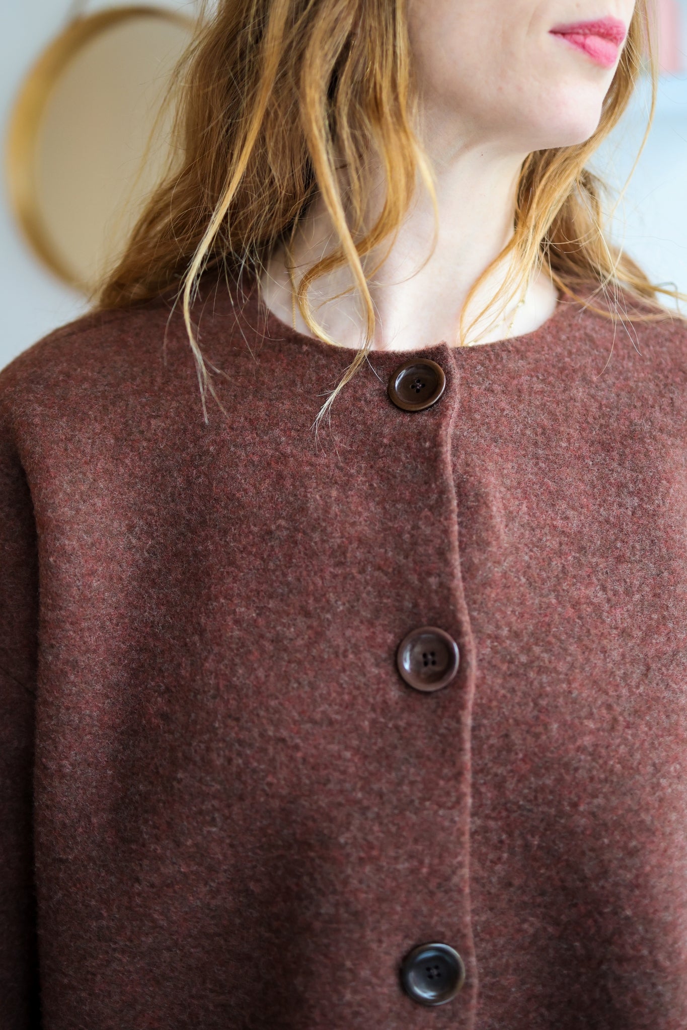 Close-up of a woman wearing a brown cardigan with buttons.