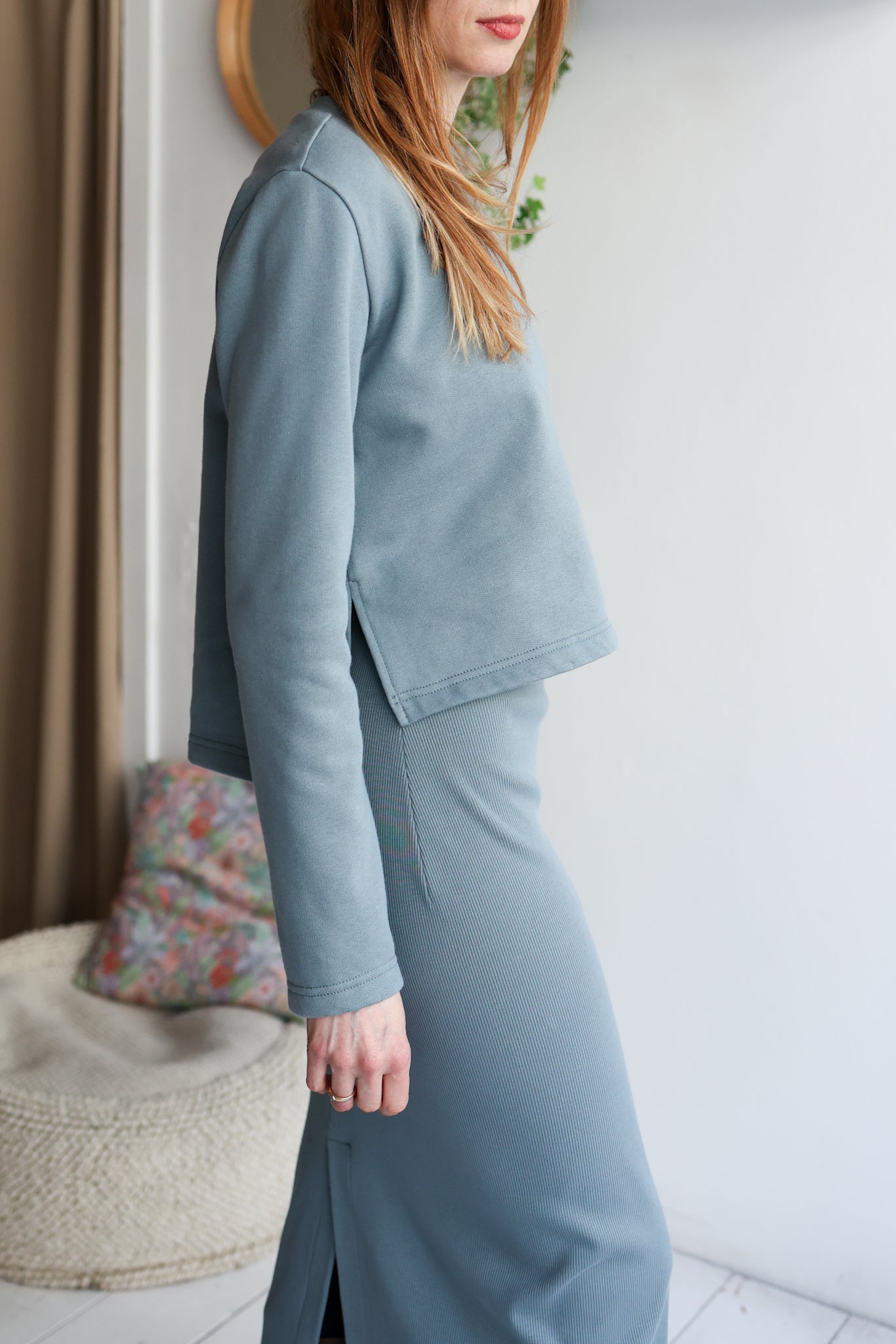 Woman wearing a light blue suit standing indoors with a neutral background