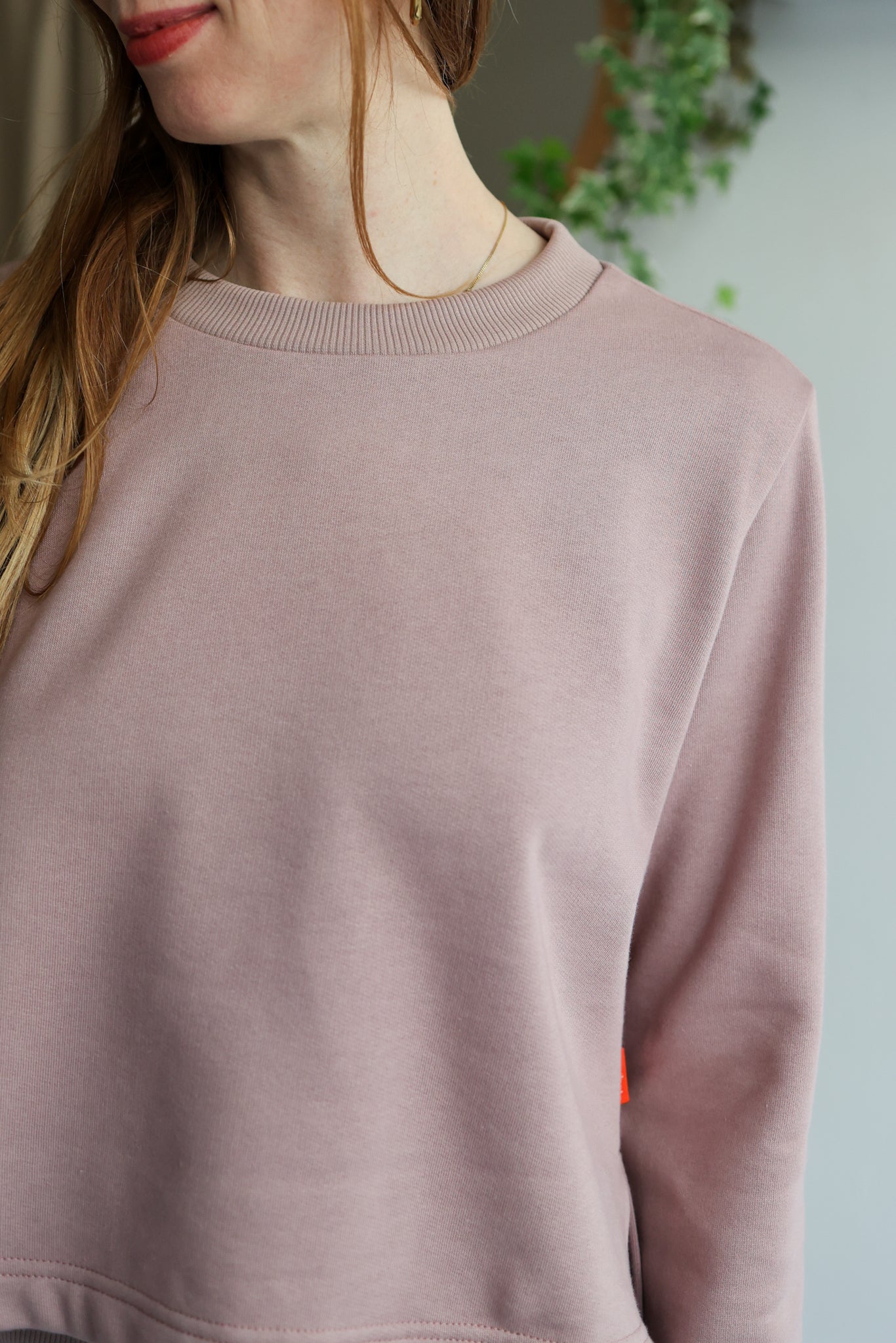 Close-up of a person wearing a mauve sweater with a blurred background