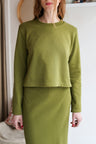 Person wearing a green long-sleeve top and skirt set indoors.