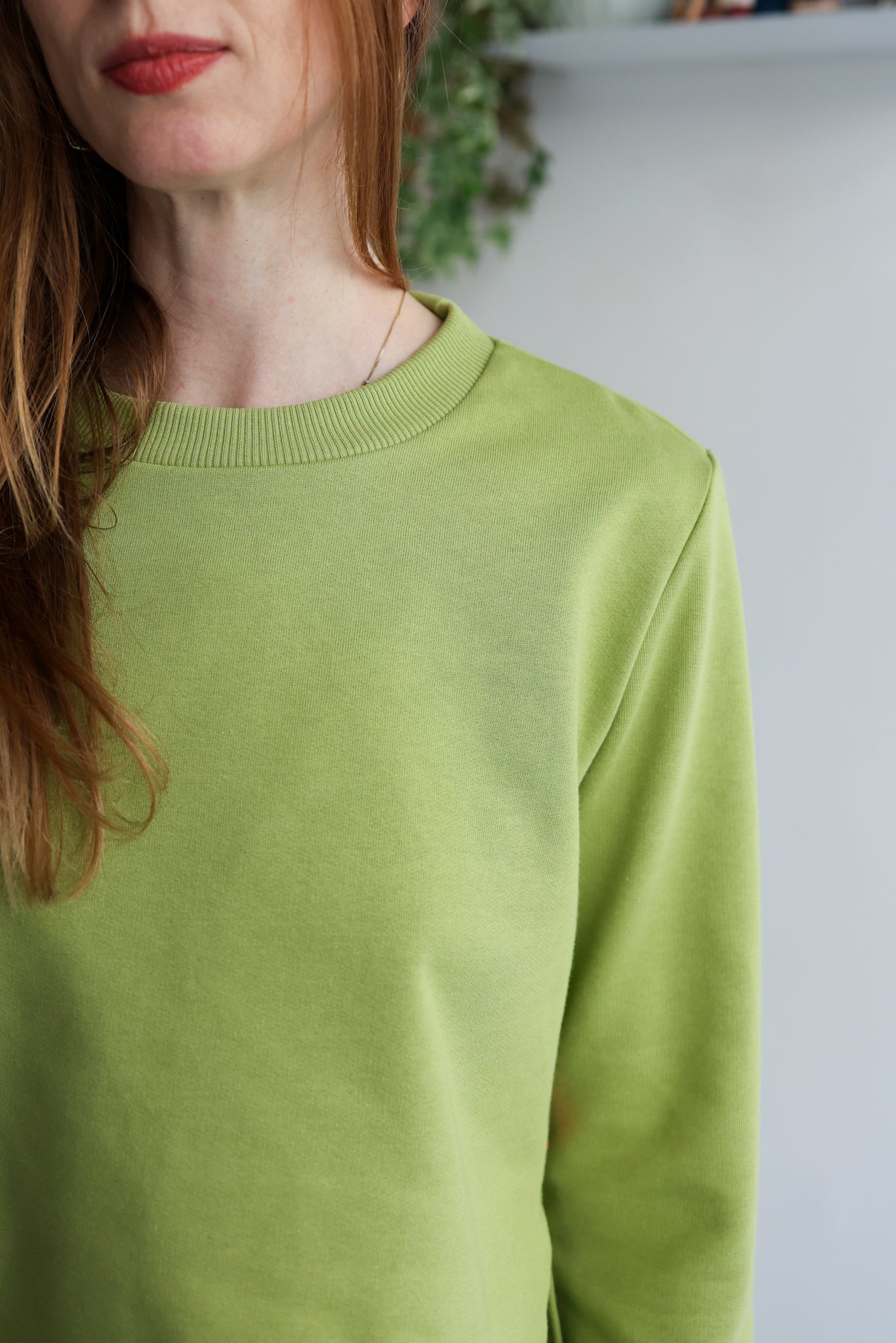 Person wearing a green sweater with a blurred background