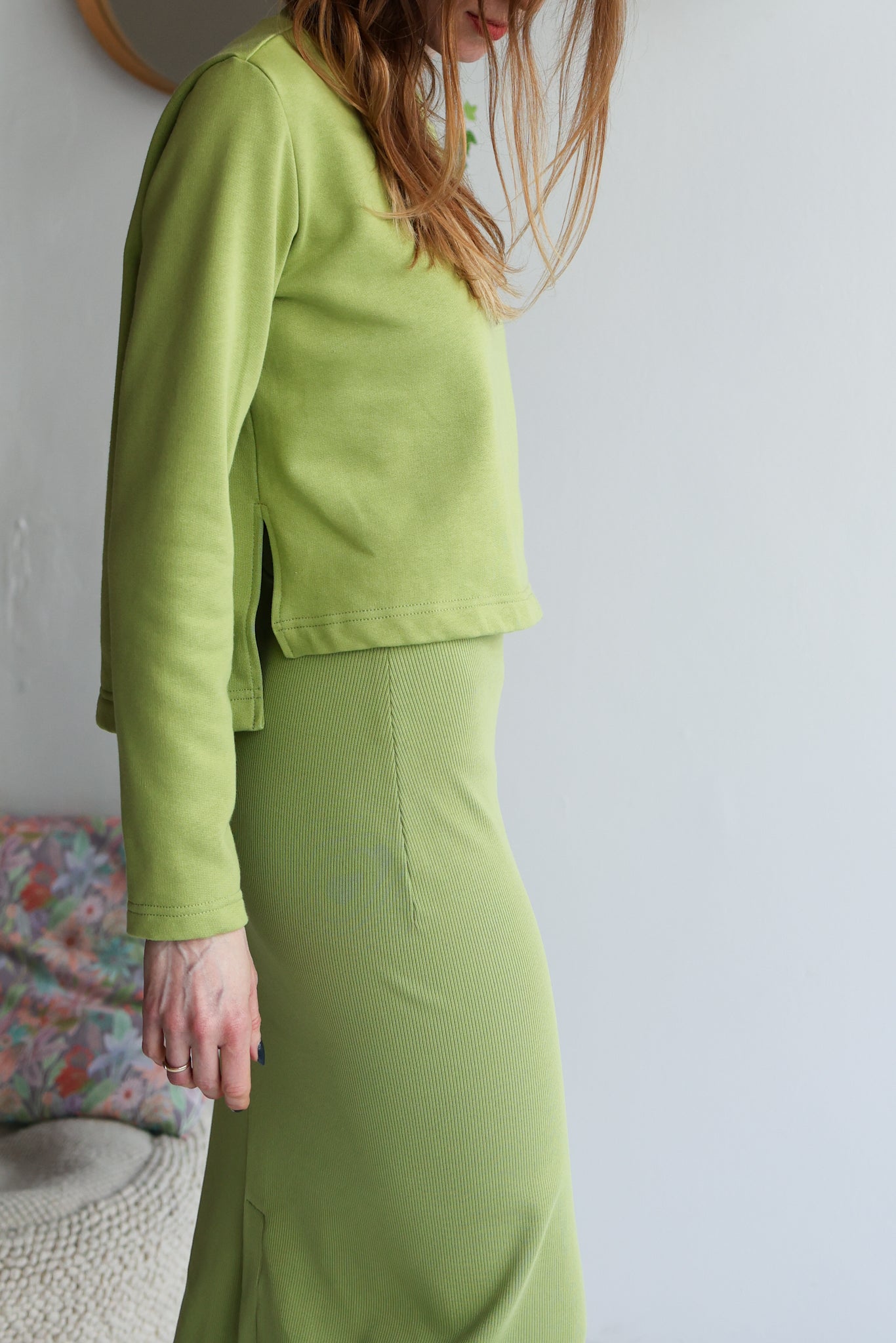 Person wearing a green outfit against a plain background