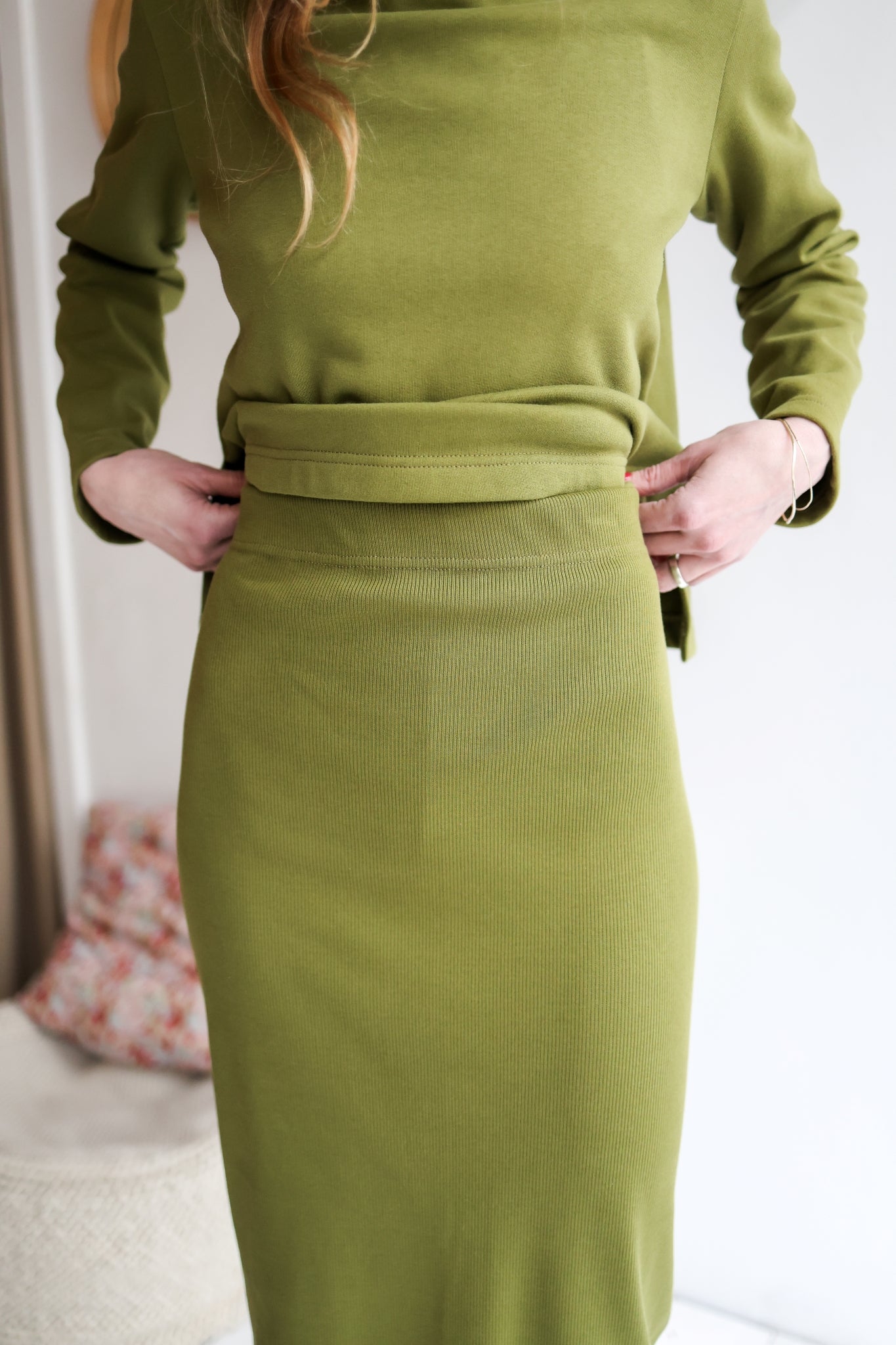 Green ribbed dress worn by a person with a neutral background.