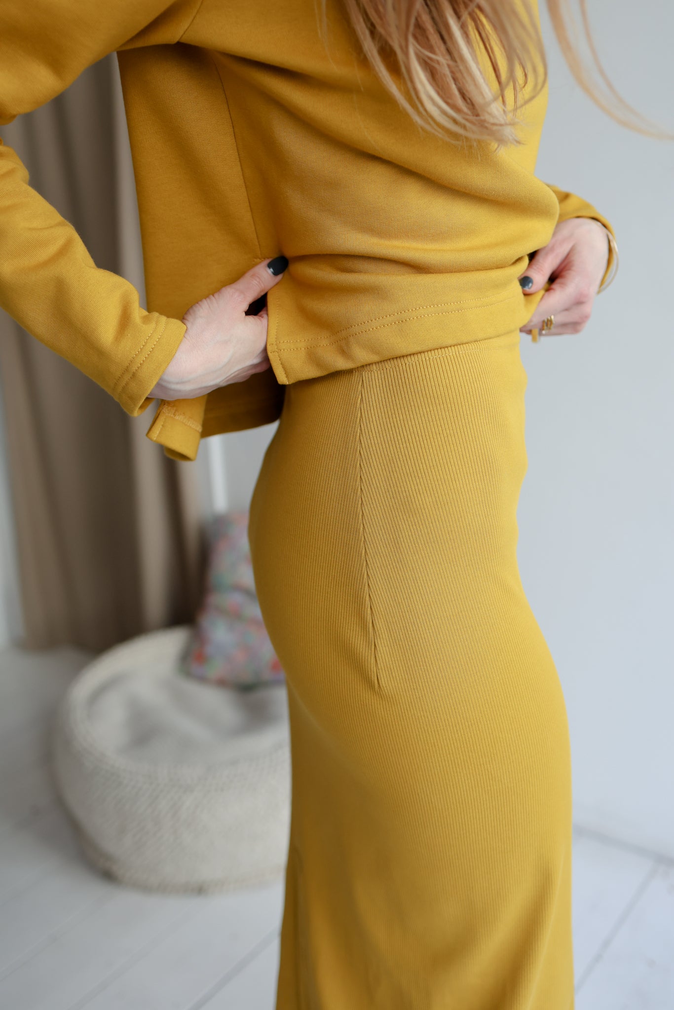 Person wearing a mustard yellow outfit with a blurred background