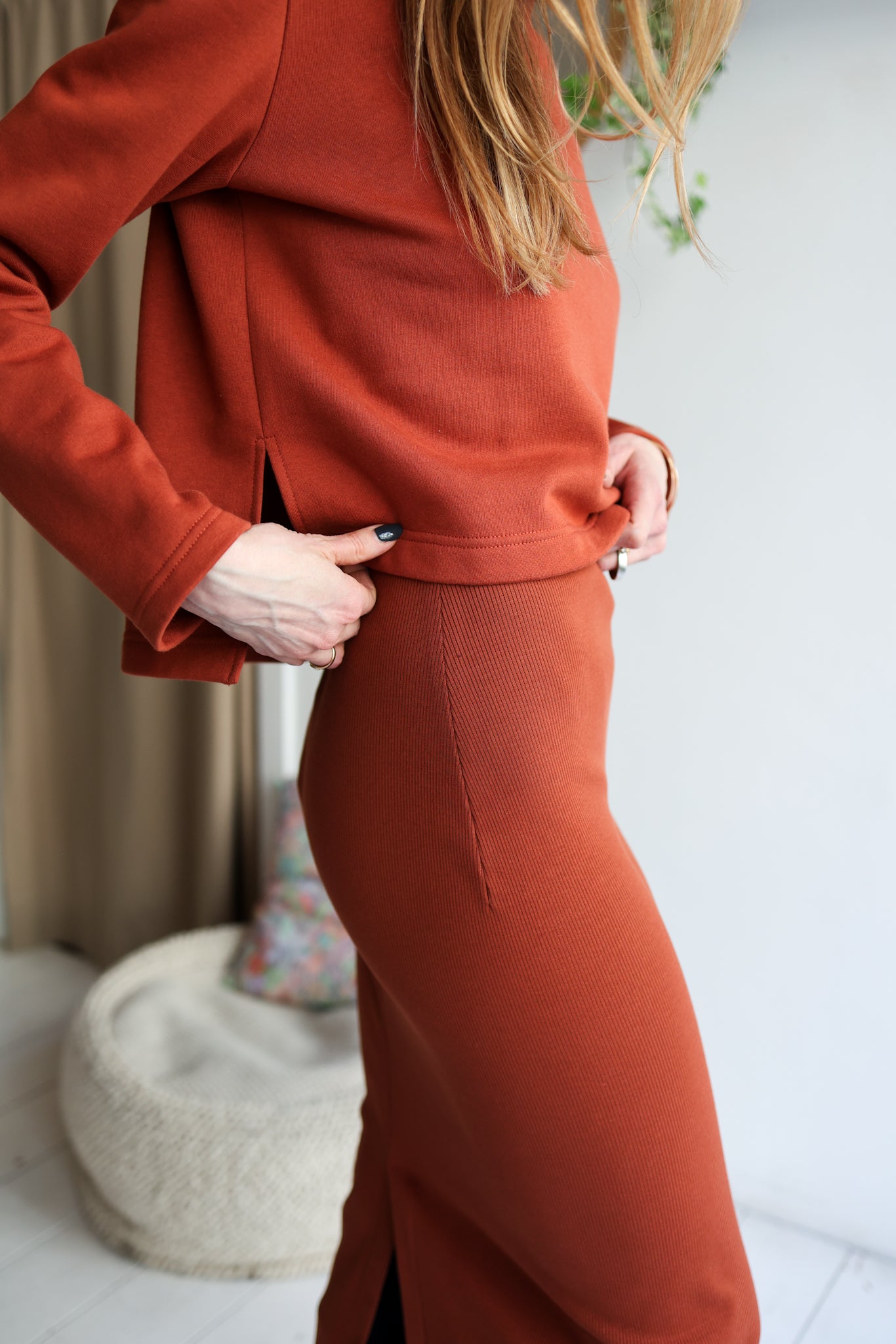 Person wearing a rust-colored outfit with a blurred background