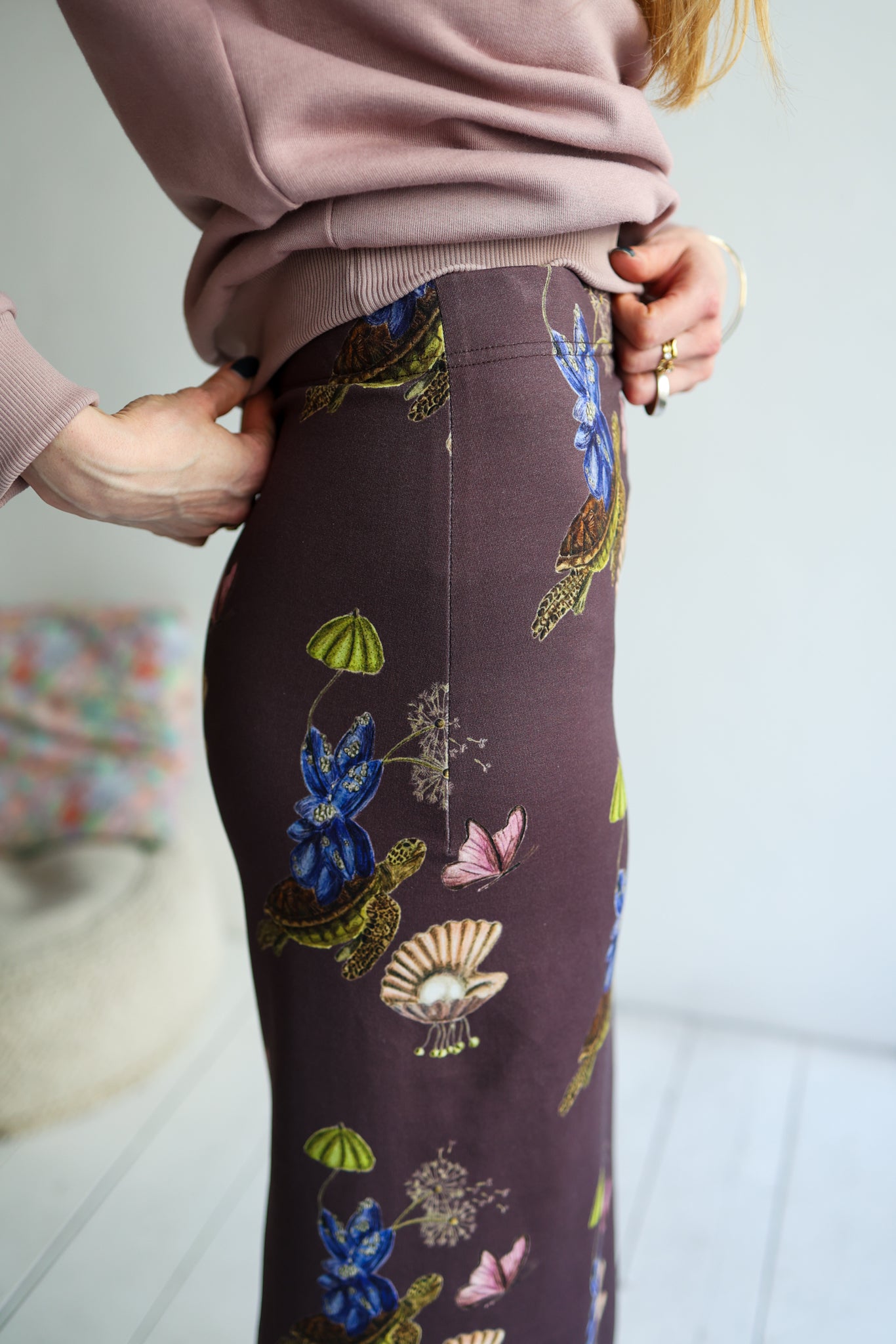 Person wearing a floral-patterned skirt with a blurred background