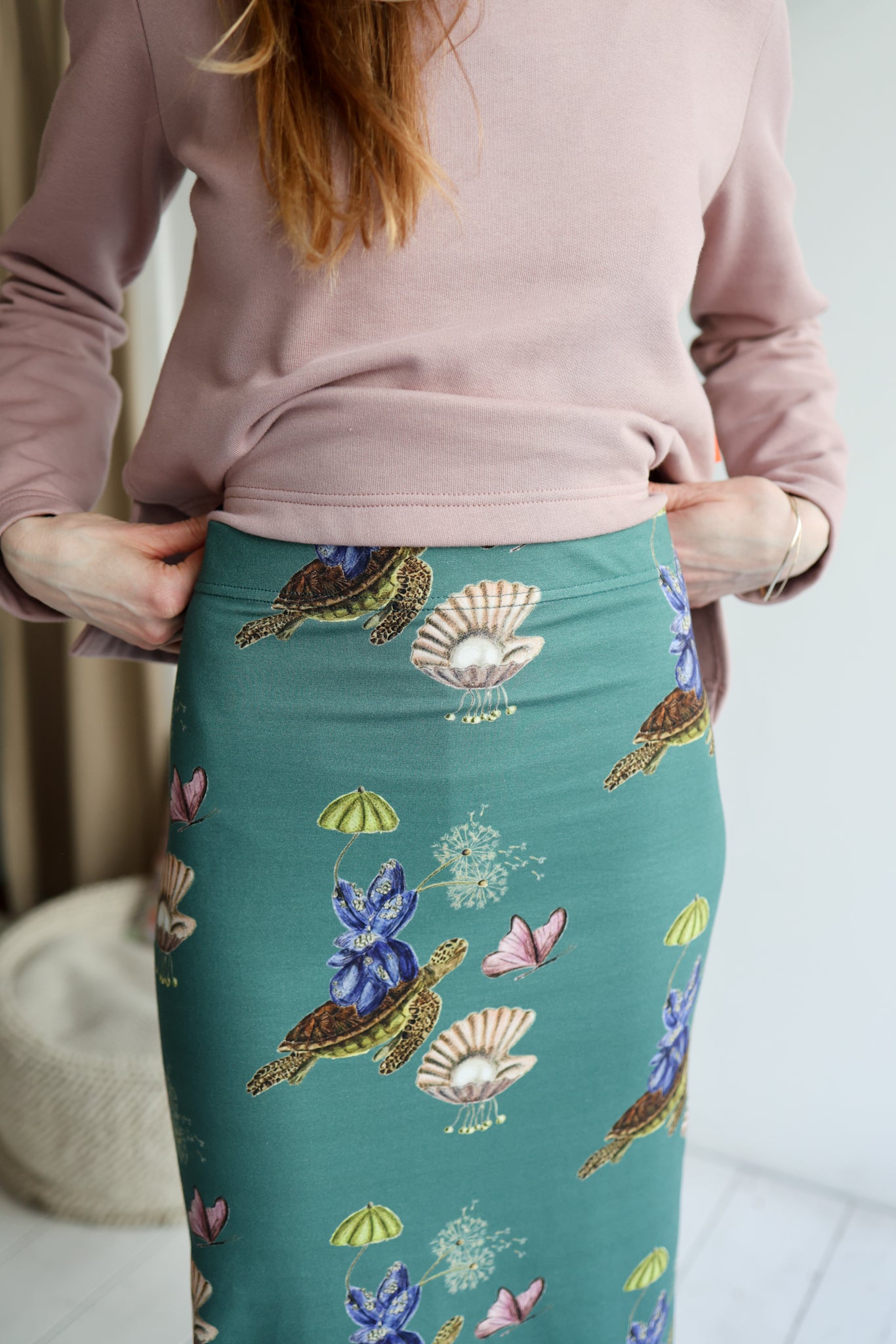 Person wearing a pink top and teal skirt with nature-themed design.