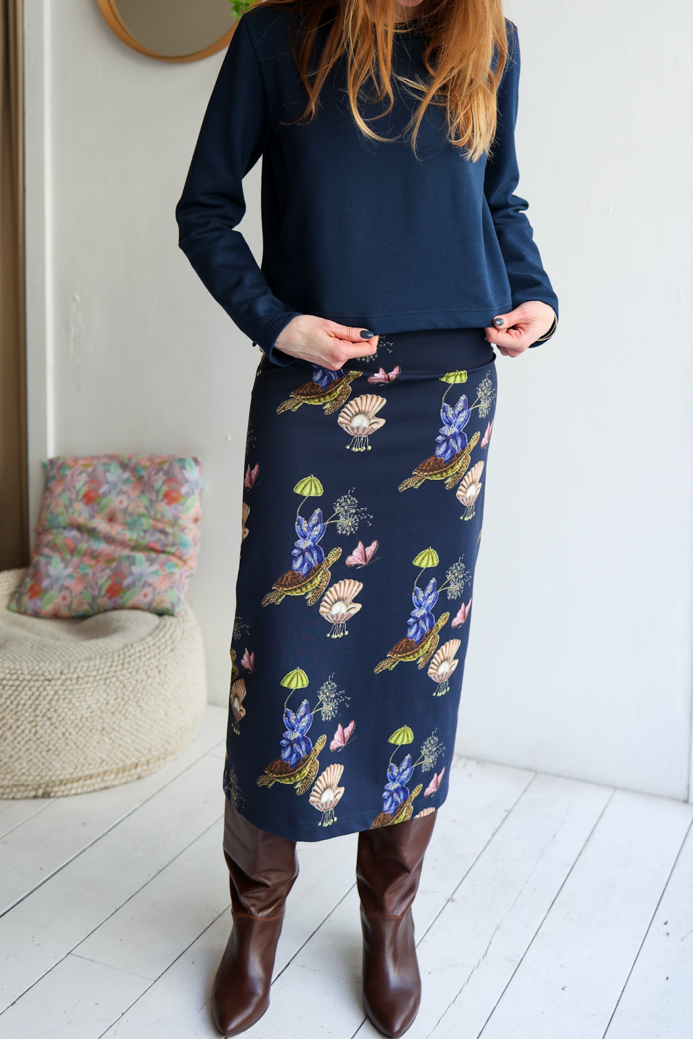 Person wearing a navy skirt with floral and nature-themed design indoors.