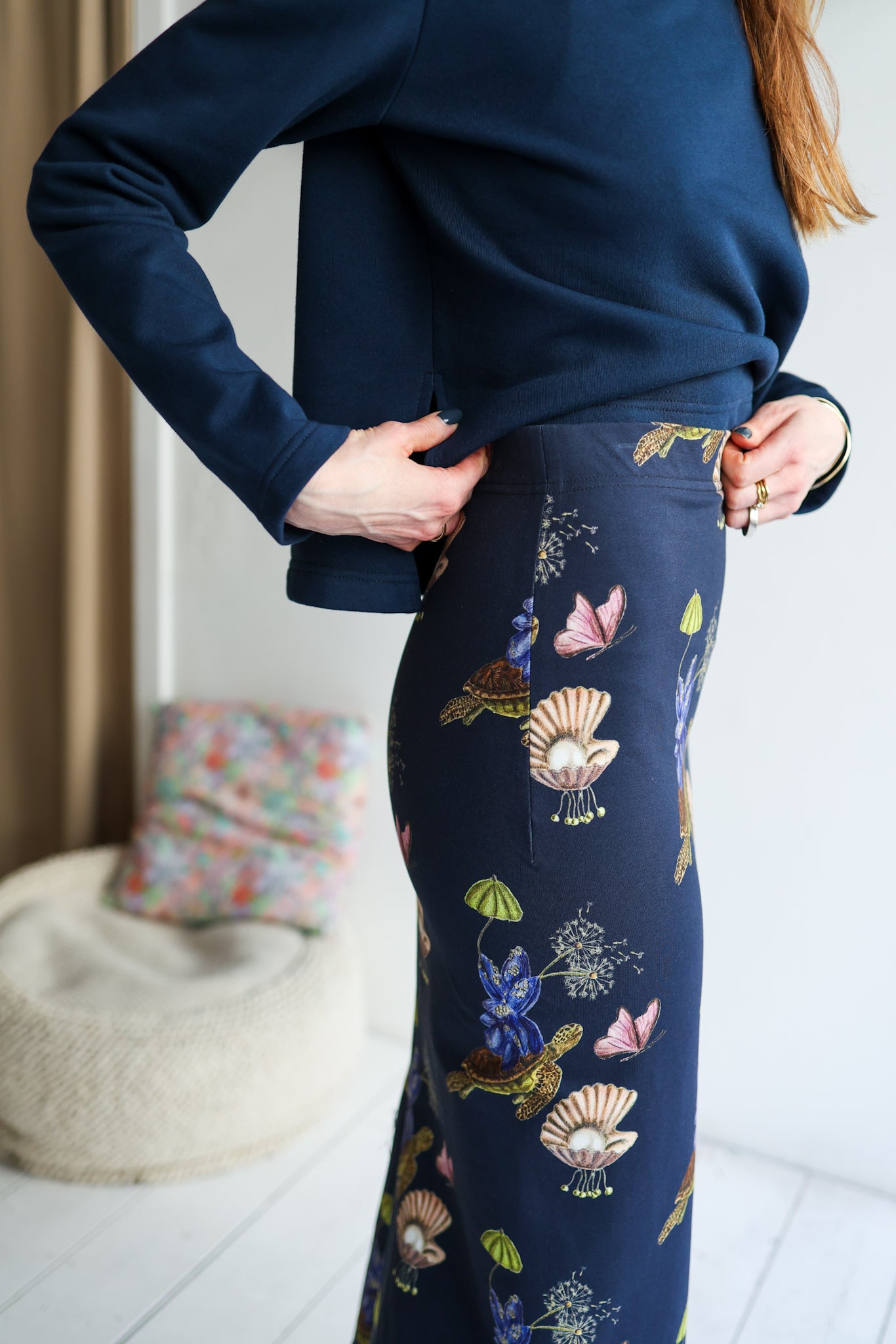 Person wearing a navy blue outfit with floral patterns in a room.