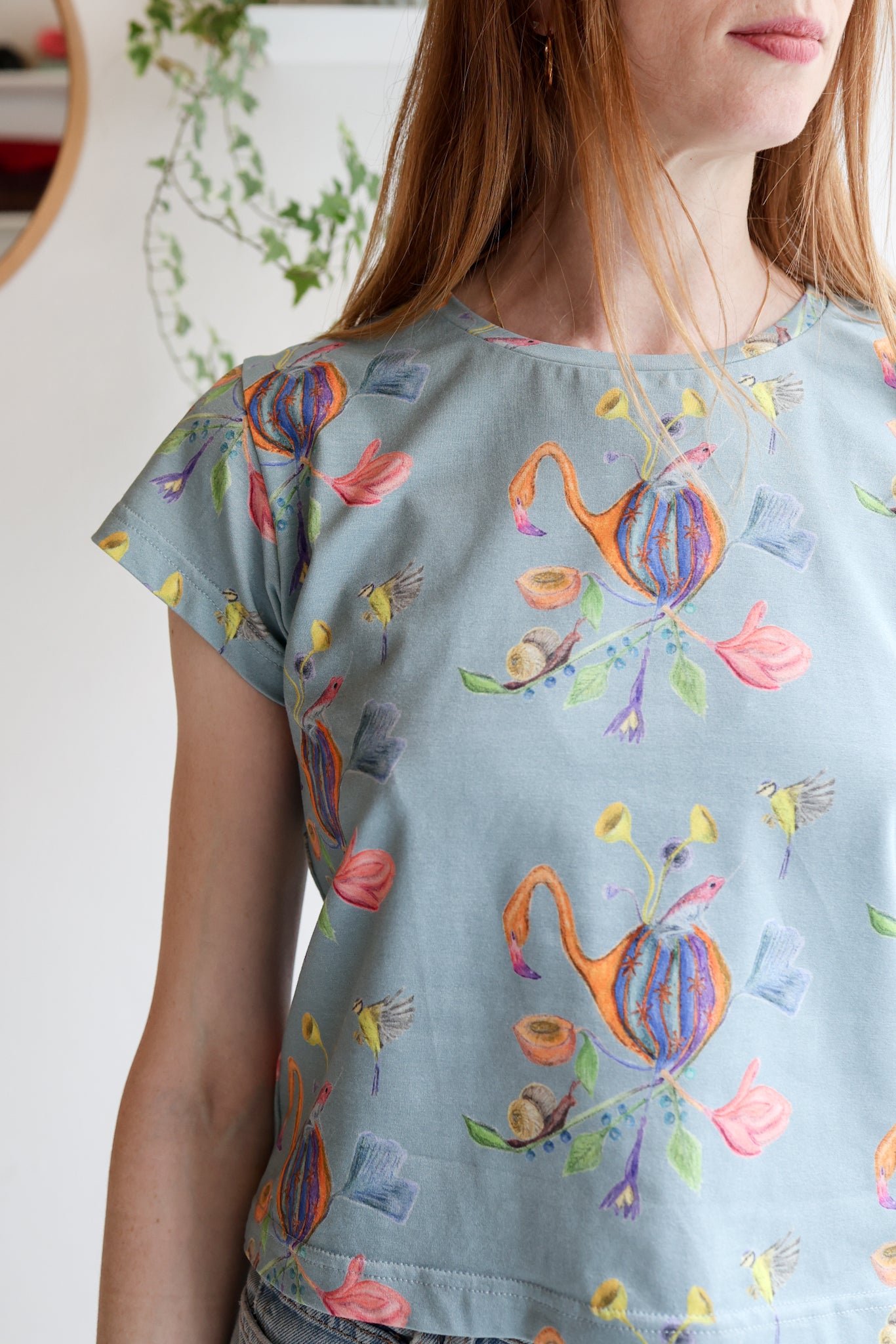 Woman wearing a blue t-shirt with colorful patterns indoors.