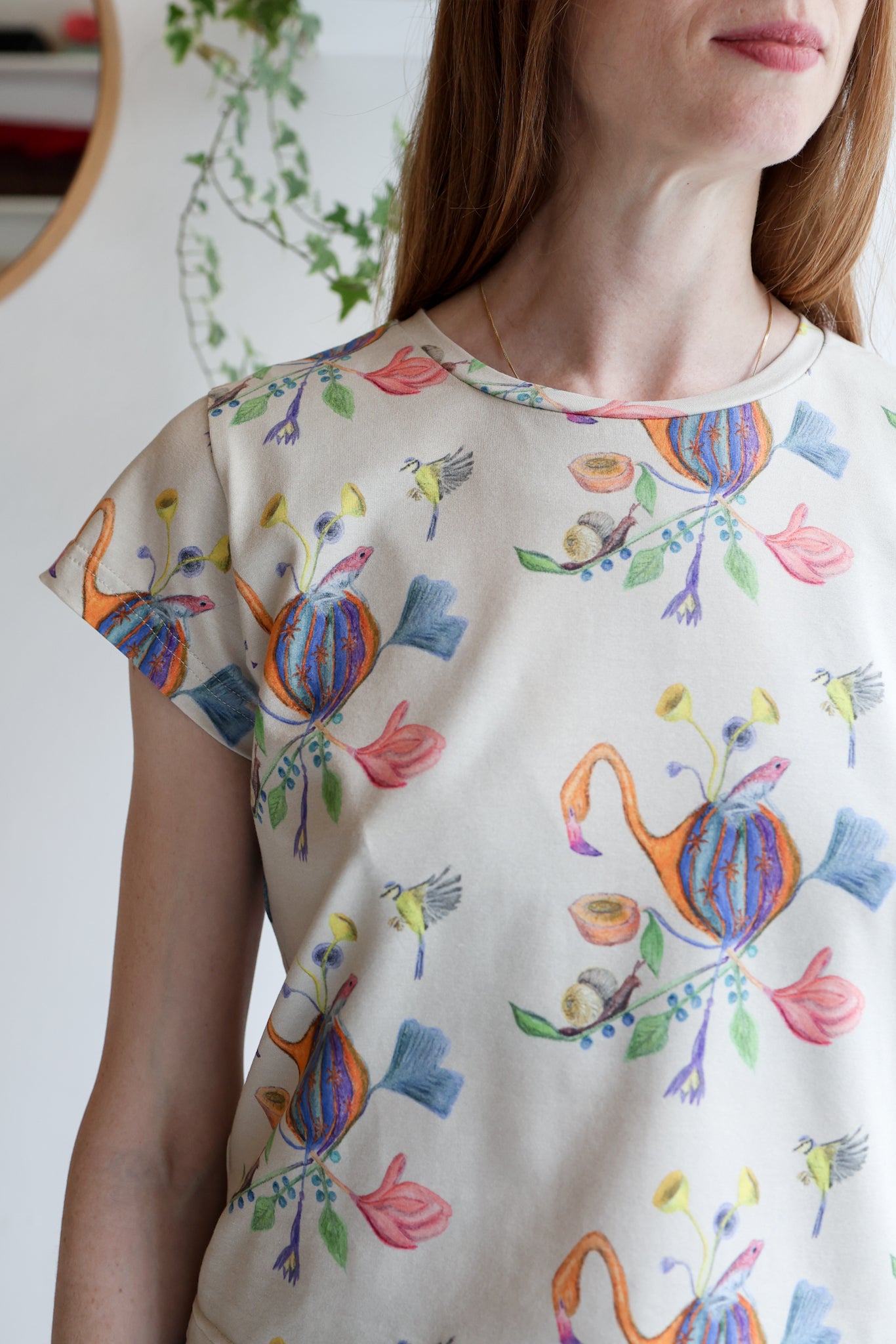 Woman wearing a beige t-shirt with colorful patterns indoors.